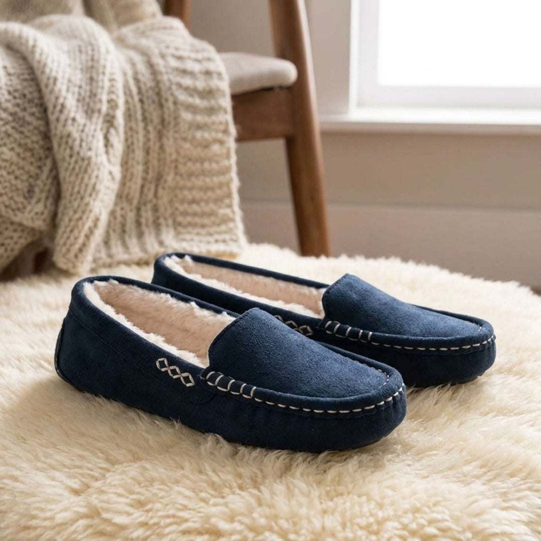 navy blue moccasin slippers with faux fur lining on white fluffy rug