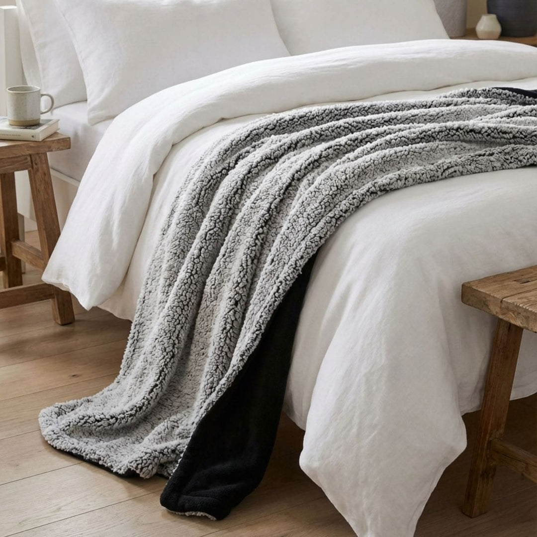 grey blanket with black coloured reverse draped over bed with white bed sheets