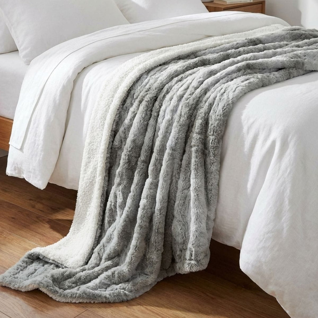grey tones faux fur blanket with sherpa fleece reverse draped over bed with white bed sheets