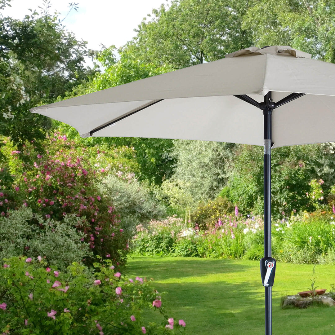 Small silver garden parasol with crank handle and tilt button with garden setting