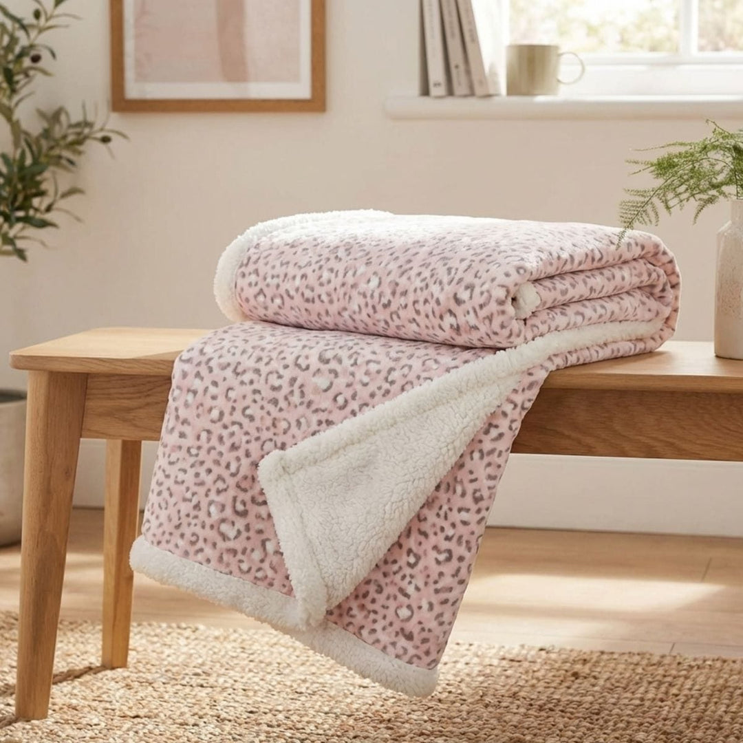 pink leopard print blanket folded and draped over wooden bench in living room olive tree in background