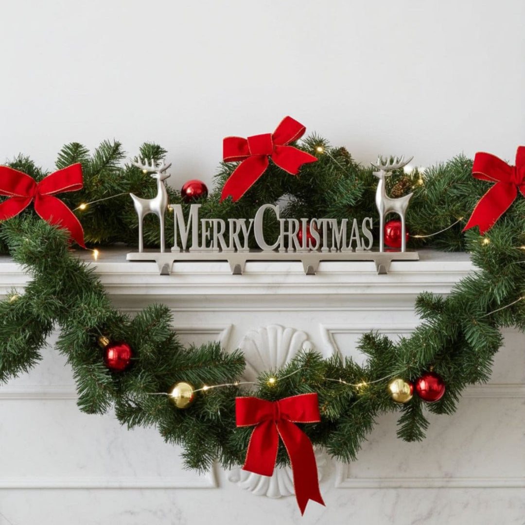 Decorative Christmas garland with red bows, gold and red ornaments, and a 'Merry Christmas' stocking hanger on a white fireplace.