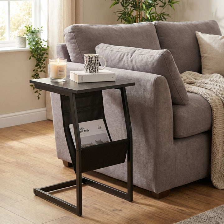 Gray sofa with a side table holding a candle, mug, and book in a living room setting.