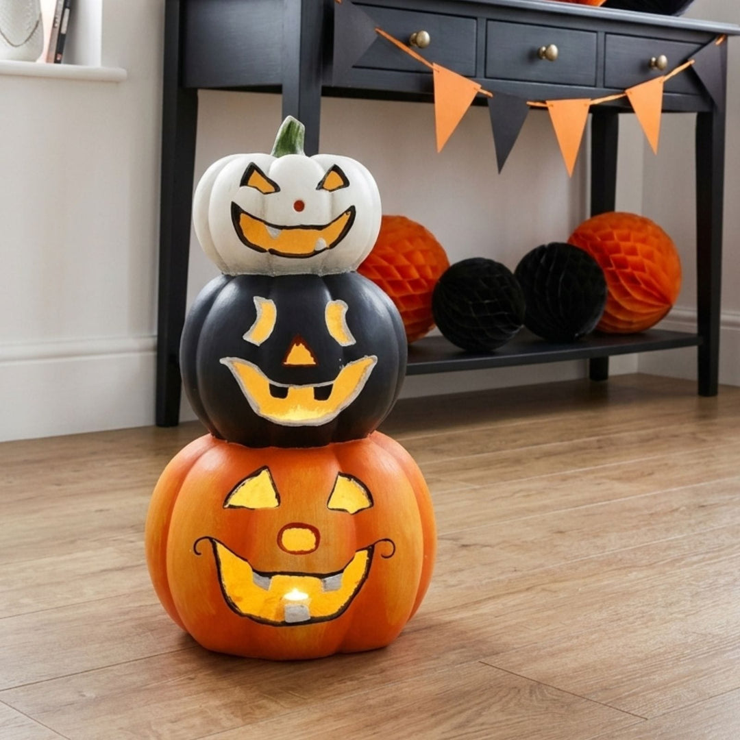 trio of stacked ceramic pumpkin decorations with led lights on wooden floor in front of black console table in hallway