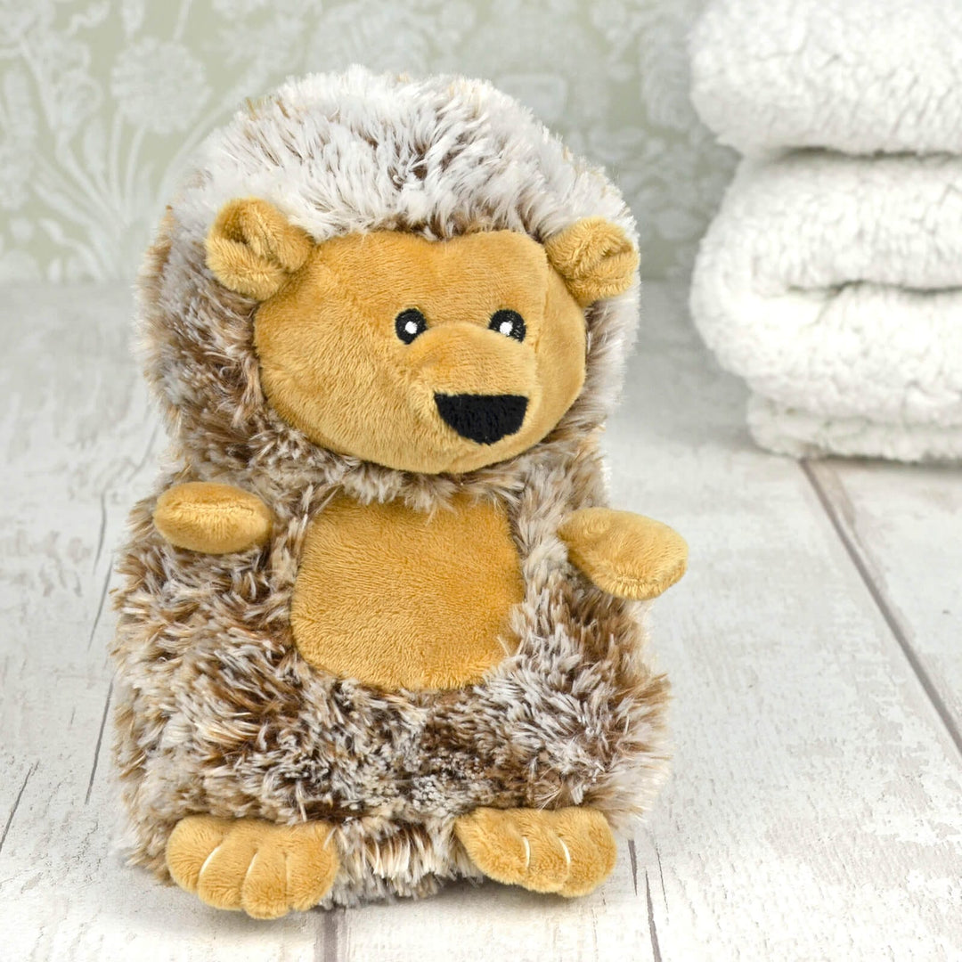 Plush hedgehog heat pack on a whitewash table with white blankets