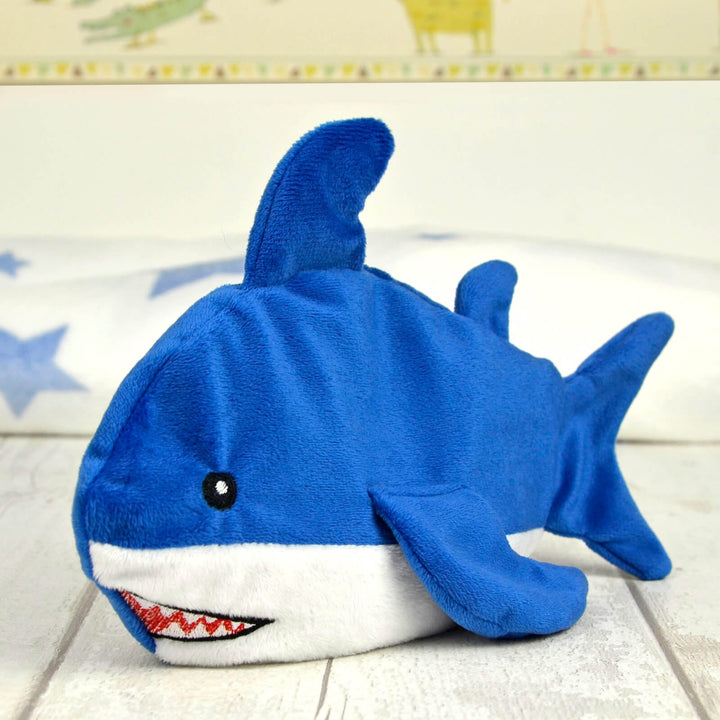 blue and white shark plush heat pack on a wooden table