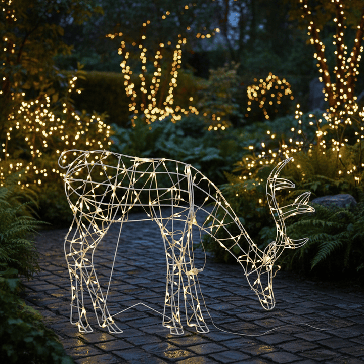 Decorative wire reindeer figure with lights in a garden setting