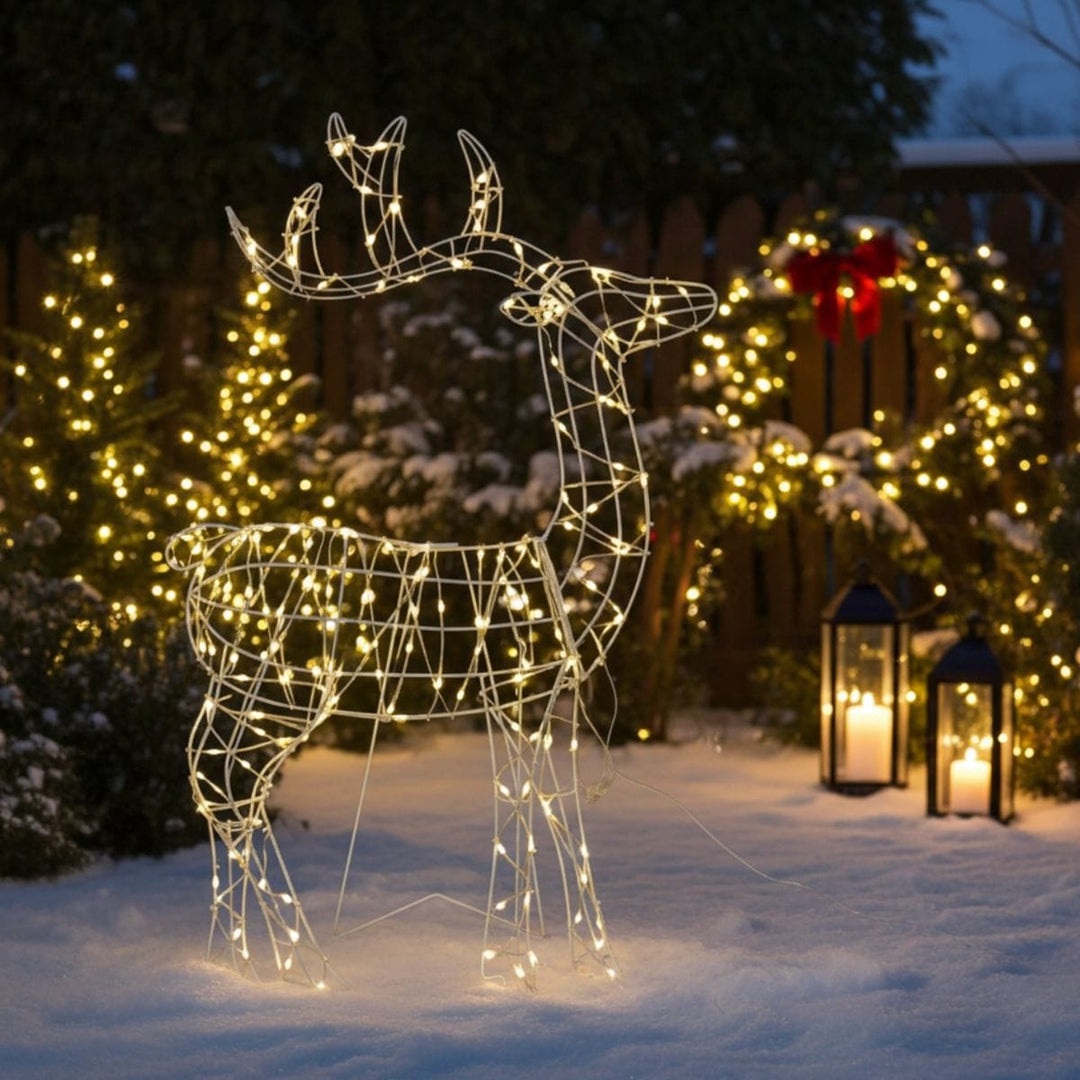 Decorative wire deer figure with lights in a snowy outdoor setting with Christmas wreaths and lanterns.