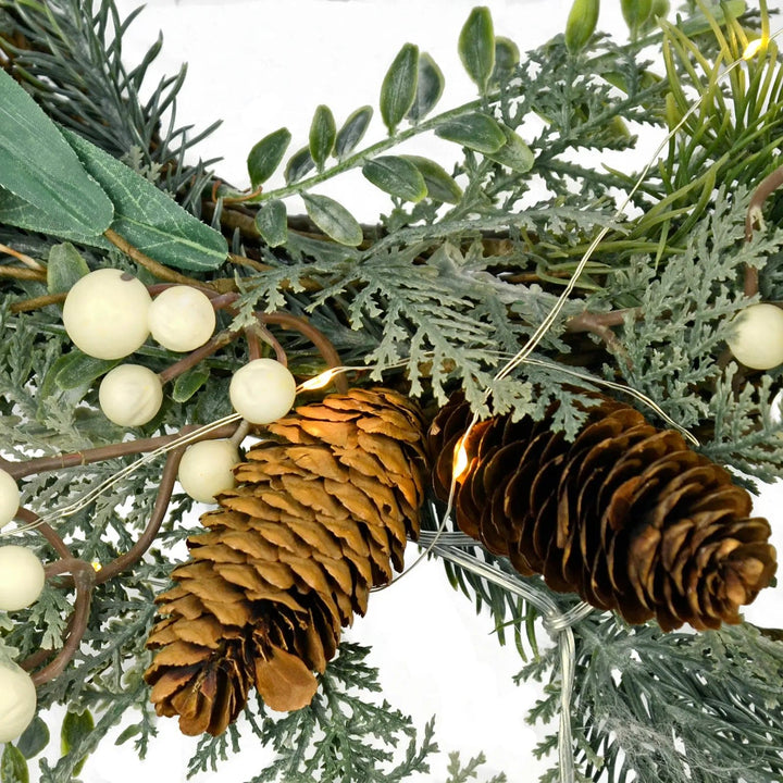 Pine cones and snowberries with white fairy lights on a Christmas wreath