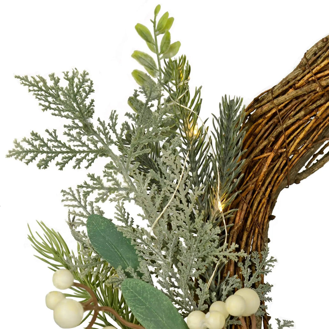 green branches and snow berries on a woven brown rattan Christmas wreath