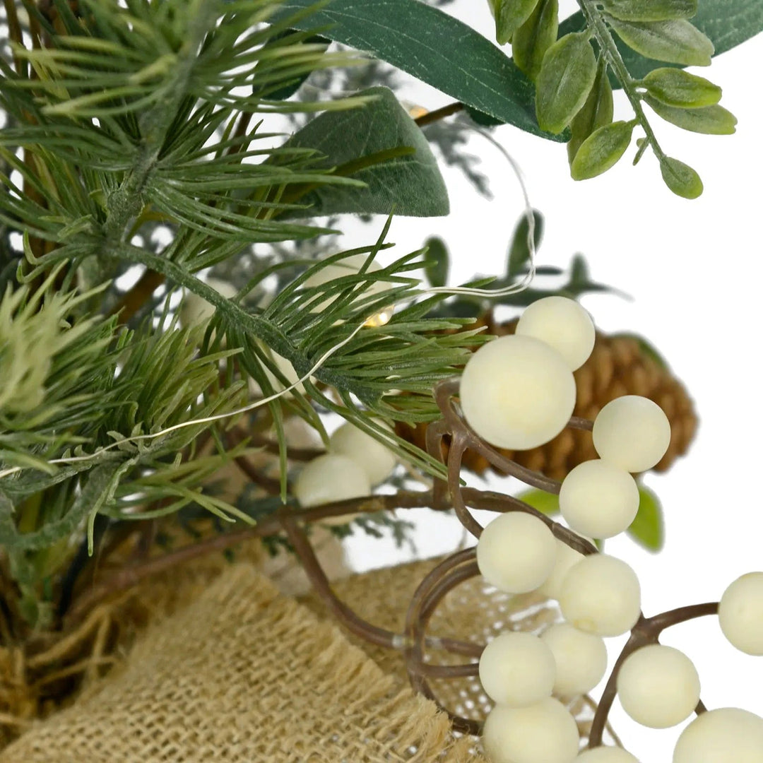 Close up of Christmas tree pine branches with white berries and mini white lights