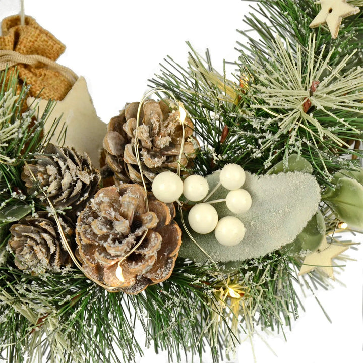 Close up of frosted artificial pine cones, branches, wooden stars, fairy lights and white berries