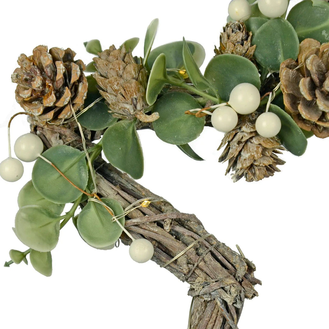 Close up detail of light up Christmas decoration with pine cones and snow berries