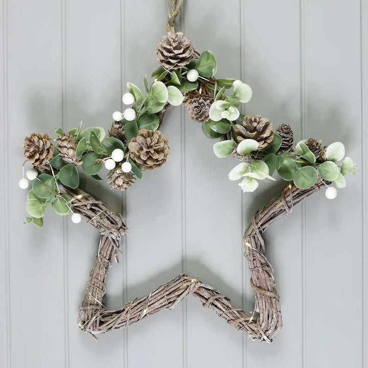 Star shape Christmas decoration with woven twig base, white berries, pone cones and fairy lights