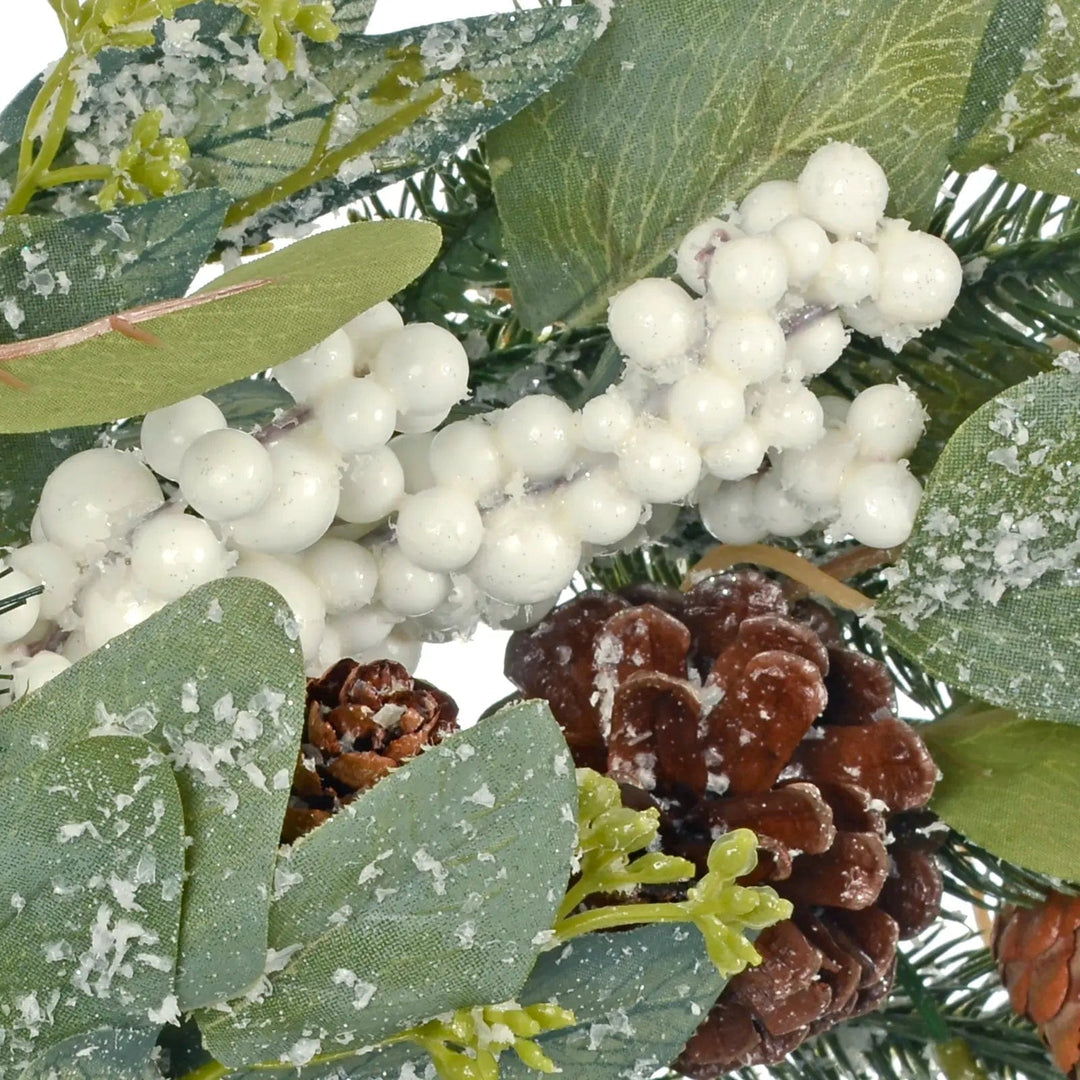 Close of frosted snowberries and pine cone on a Christmas wreath