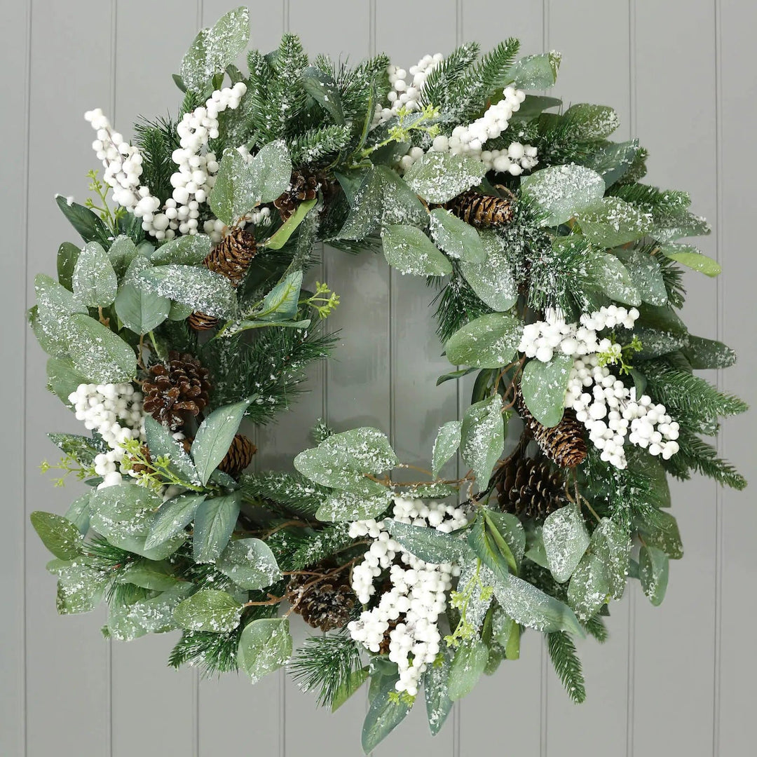 Green frosted Christmas wreath with bunches of white berries and pine cones