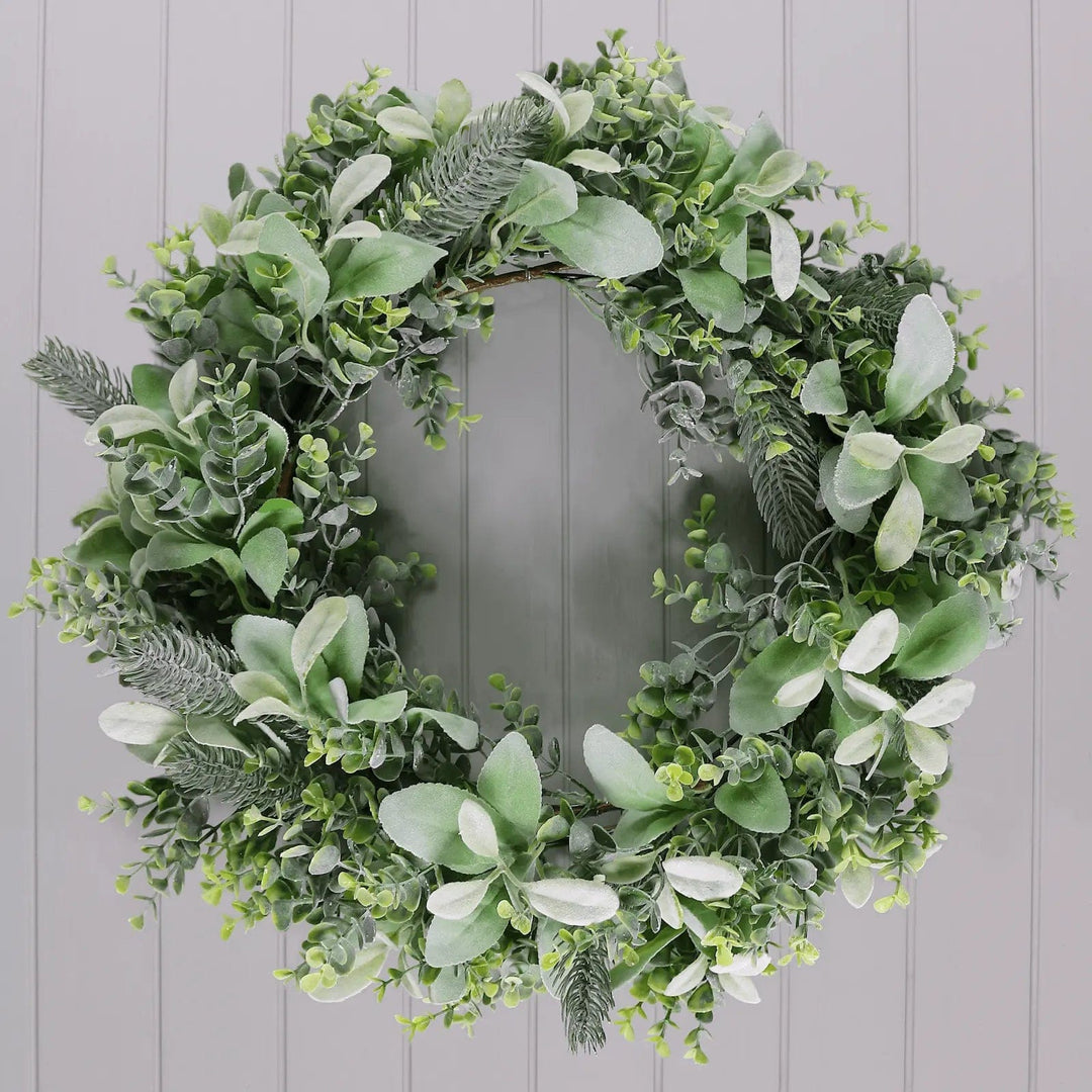 Green foliage Christmas wreath with mixed leaves on a grey panelled wall