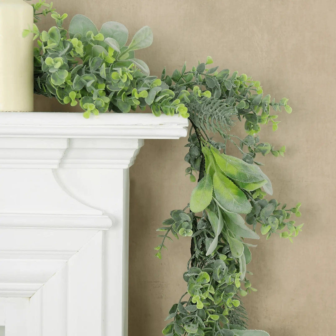 Green Christmas garland with mixed leaves draped over a mantelpiecee