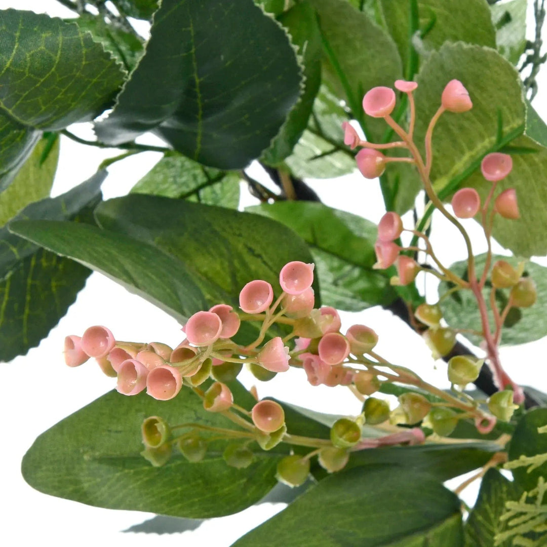 Close up of little pink flowers on a Christmas garland with green leaves