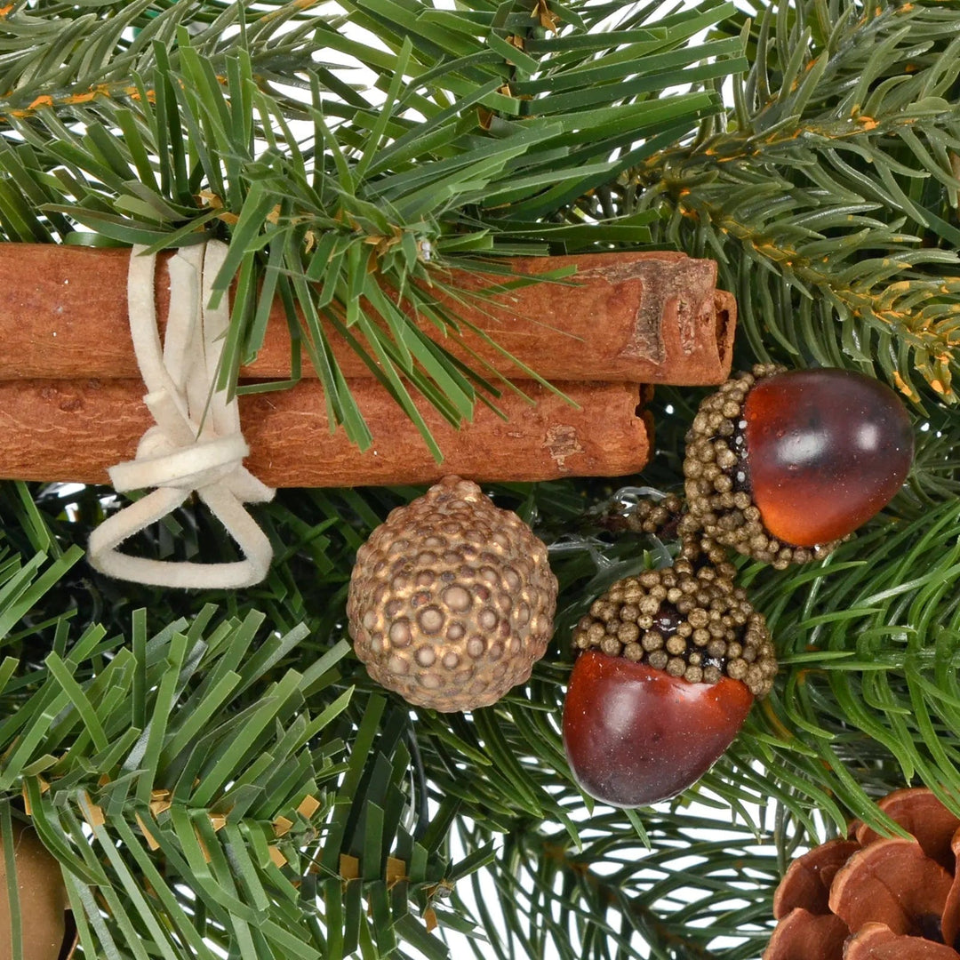 Acorns and cinnamon sticks on green pine branches of a Christmas wreath