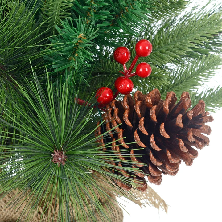 Close up of pine cone and red berries on Christmas tree with green pine branches