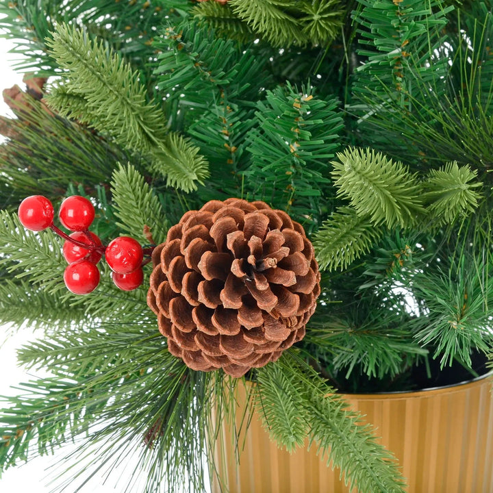 Close up of a pine cone and red berries on a green pine Christmas tree