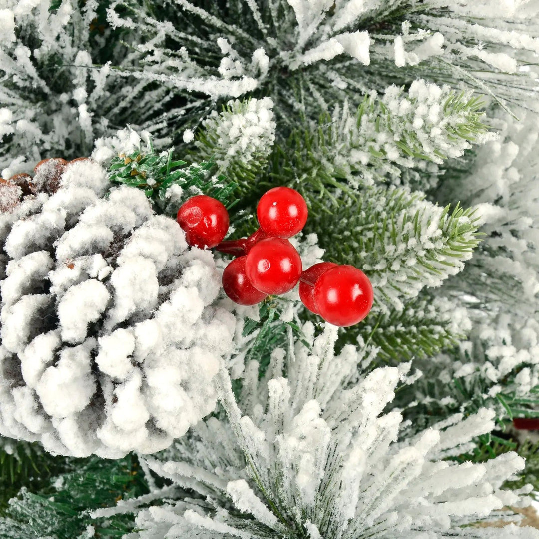 Close up of red berry cluster on a snow covered artificial green pine Christmas tree