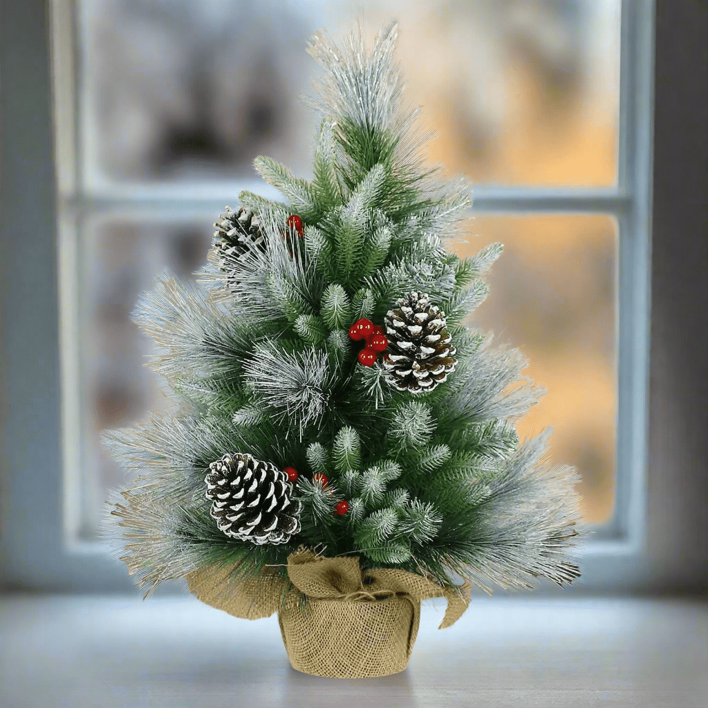 Small Christmas tree with frost covered branches, pine cones, red berries and a jute fabric covered base