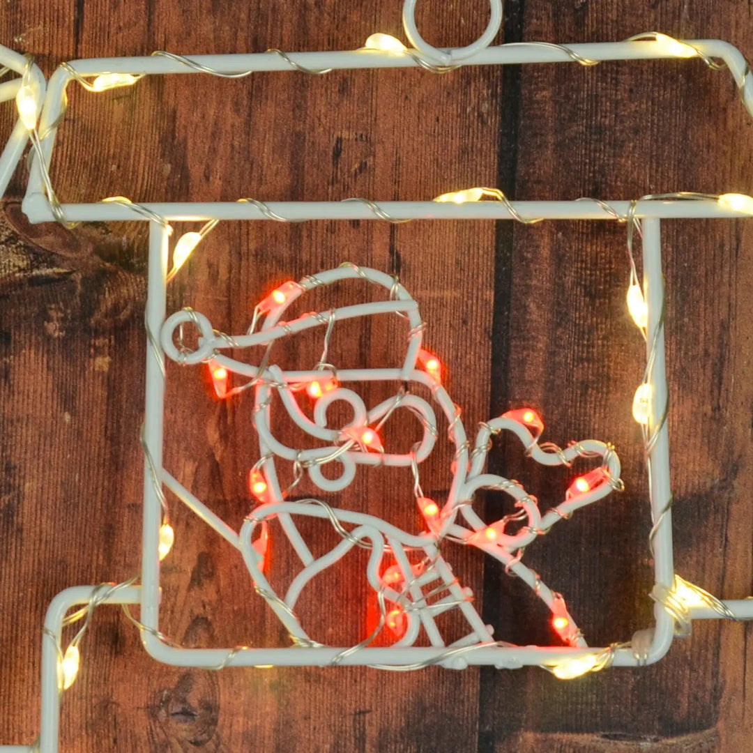 Close up of Santa lit up by red LED lights on a wooden fence