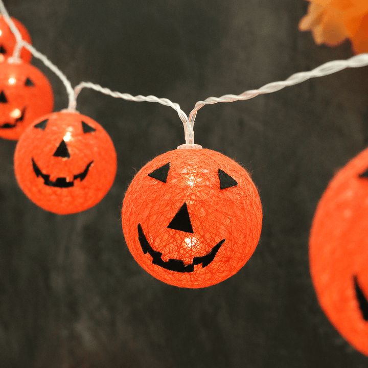 5 orange string pumpkin LED lights with warm white lights on transparent string. Pumpkin features black felt face details.