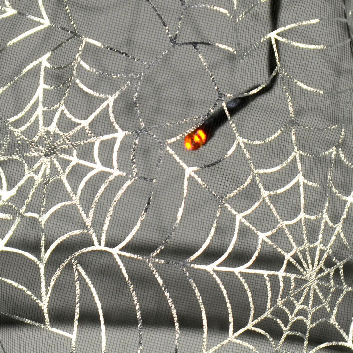 Close up of an orange LED light inside silver spder web pattern witch hat hanging light