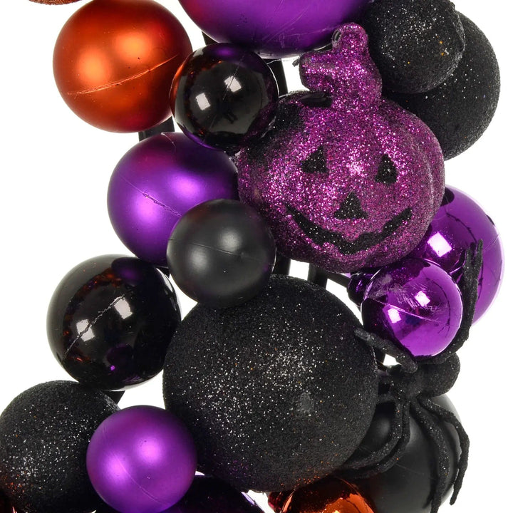 Purple glitter pumpkin, black glitter spider, black purple and orange baubles on a Halloween door wreath