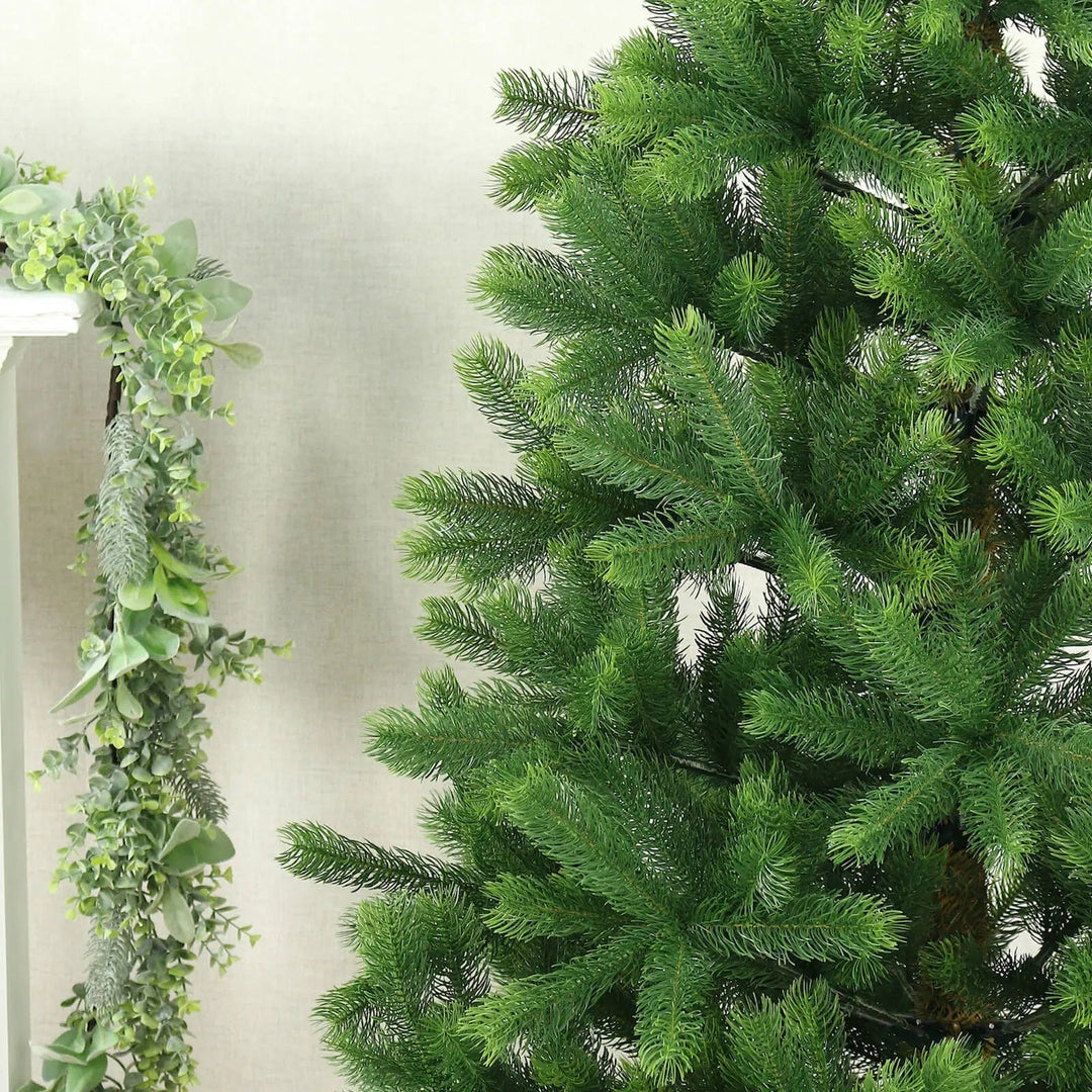 Full green pine branches on large Christmas tree beside a fireplace with green foliage garland