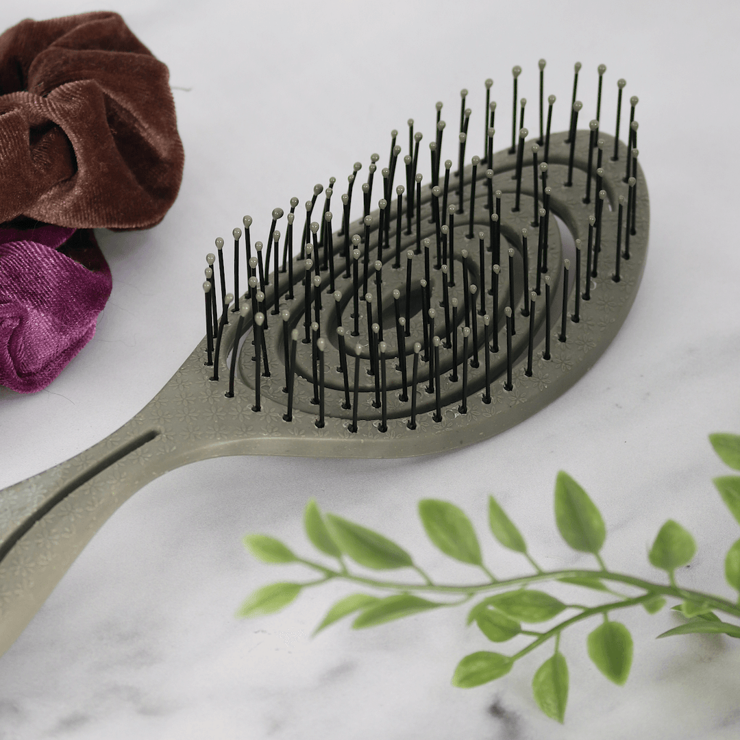 detail shot of grey hair brush highlighting grey round bristle ends beside hair ties