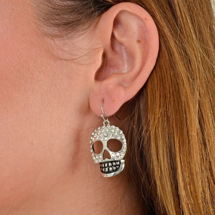 Model wearing silver skull drop earrings with diamante jewels