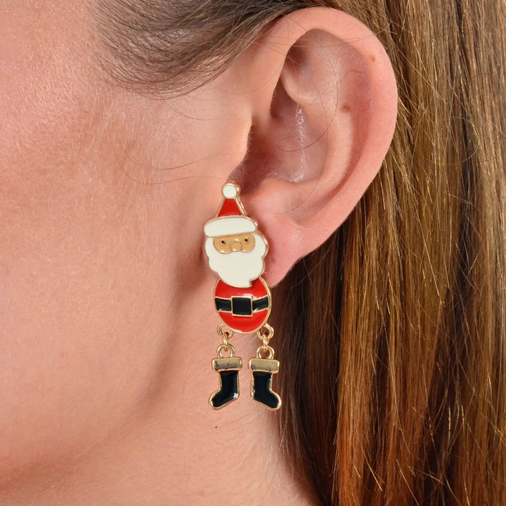 Model wearing novelty Santa Christmas earrings in red, white and gold with black belt and boots