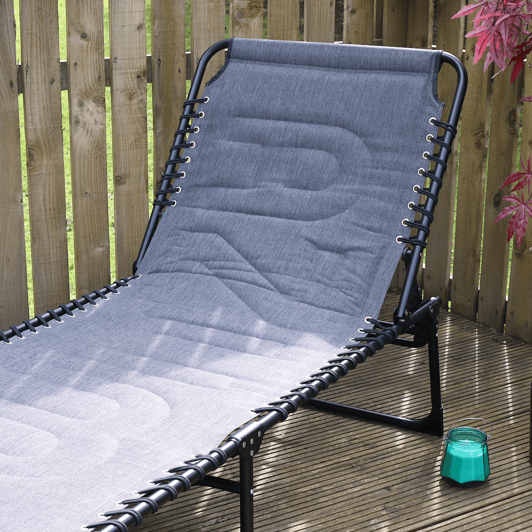 dark grey padded material on extra large sun lounger on wooden patio space