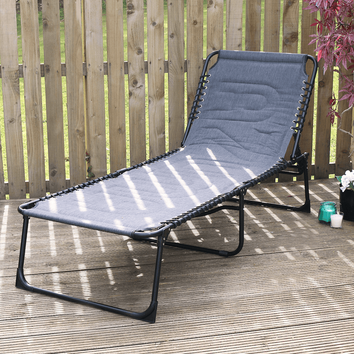 dark grey large padded sun lounger on wooden patio space beside candle and red maple tree