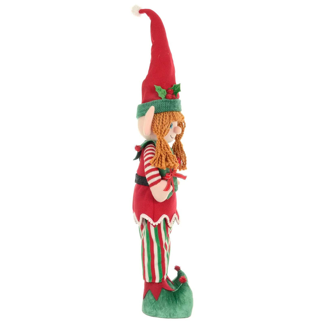 Side view of Christmas Girl elf Christmas figure standing with green, red and white fabric clothing