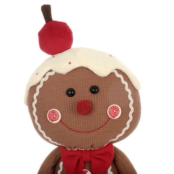 Face detail of a Christmas gingerbread fabric figure with fleece icing and red cherry on top