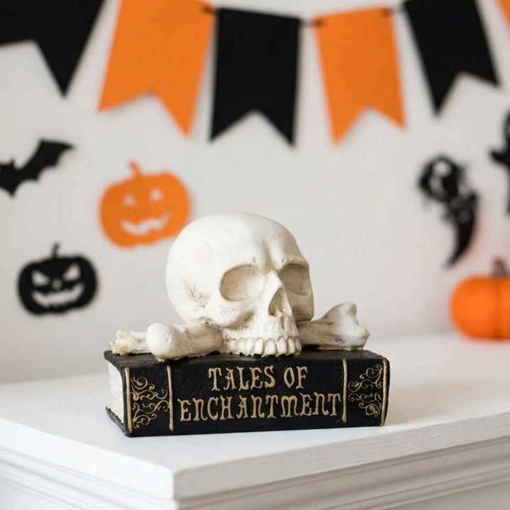 A Halloween decoration featuring a white skull and crossbones resting on a black book with gold lettering that reads &