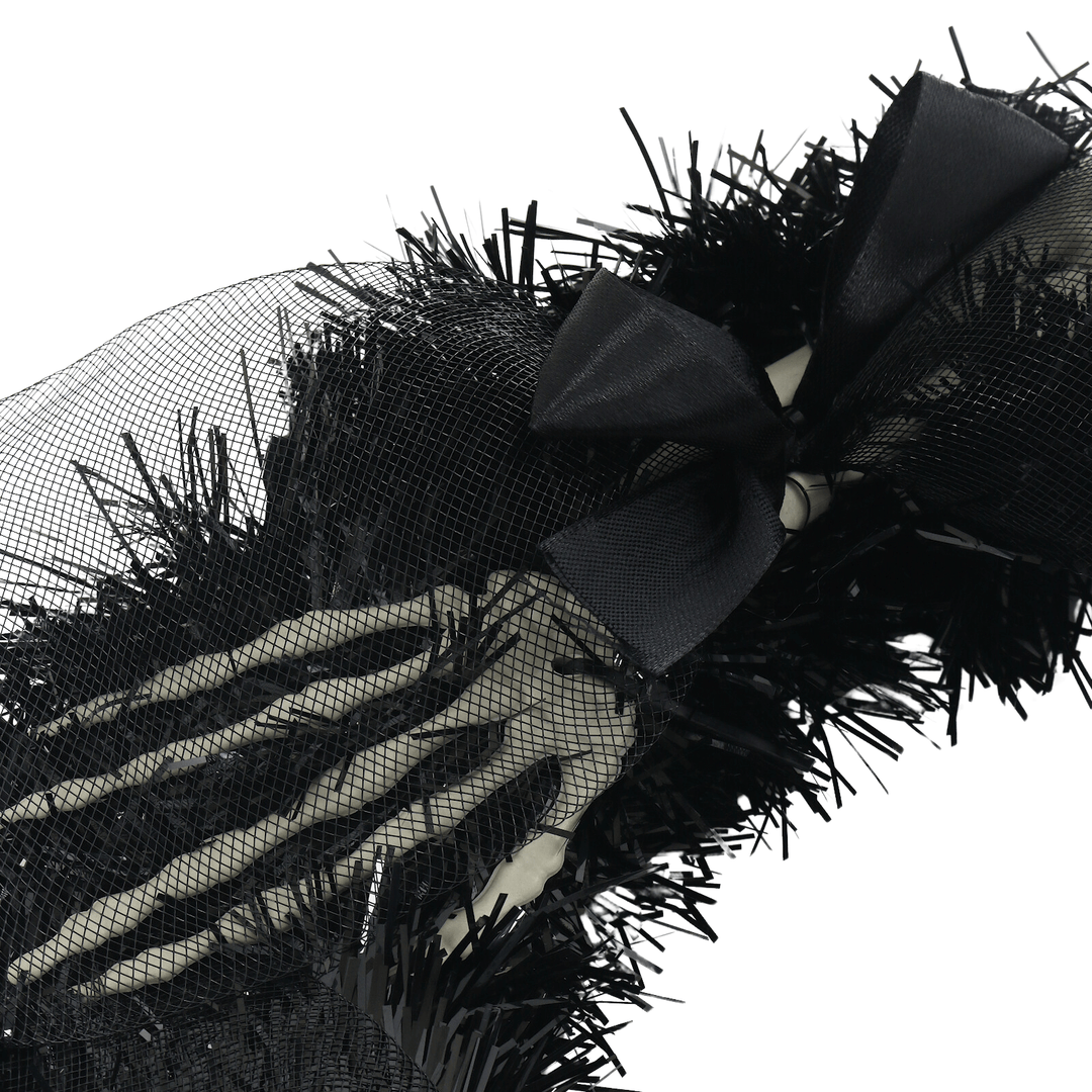 detail shot of skeleton hands on tinsel wreath with silk bow and organaza mesh material on top
