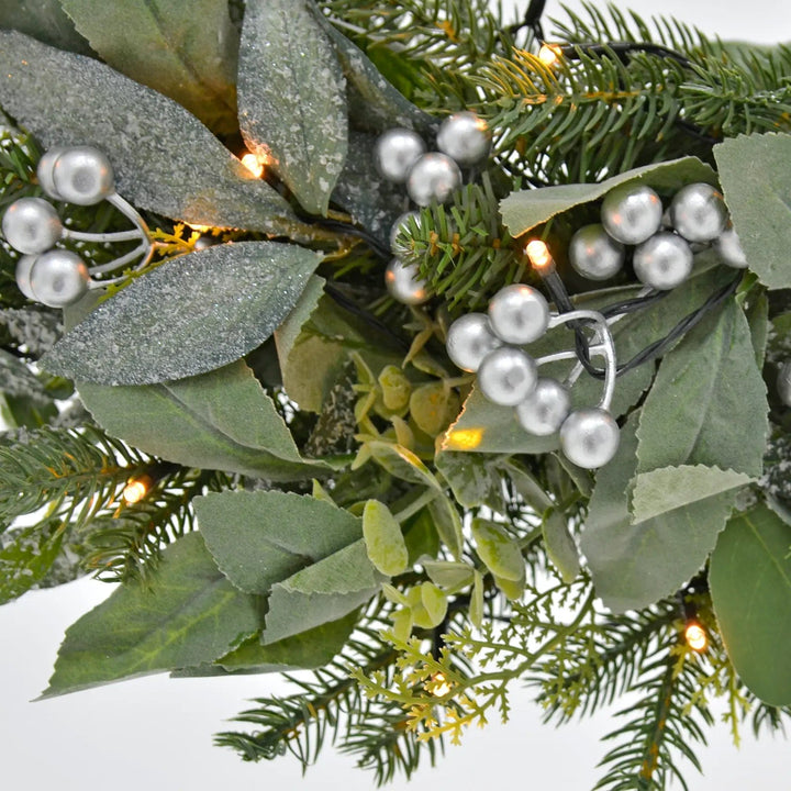 Close up of Christmas wreath with LED lights, silver berries and mixed green leaves