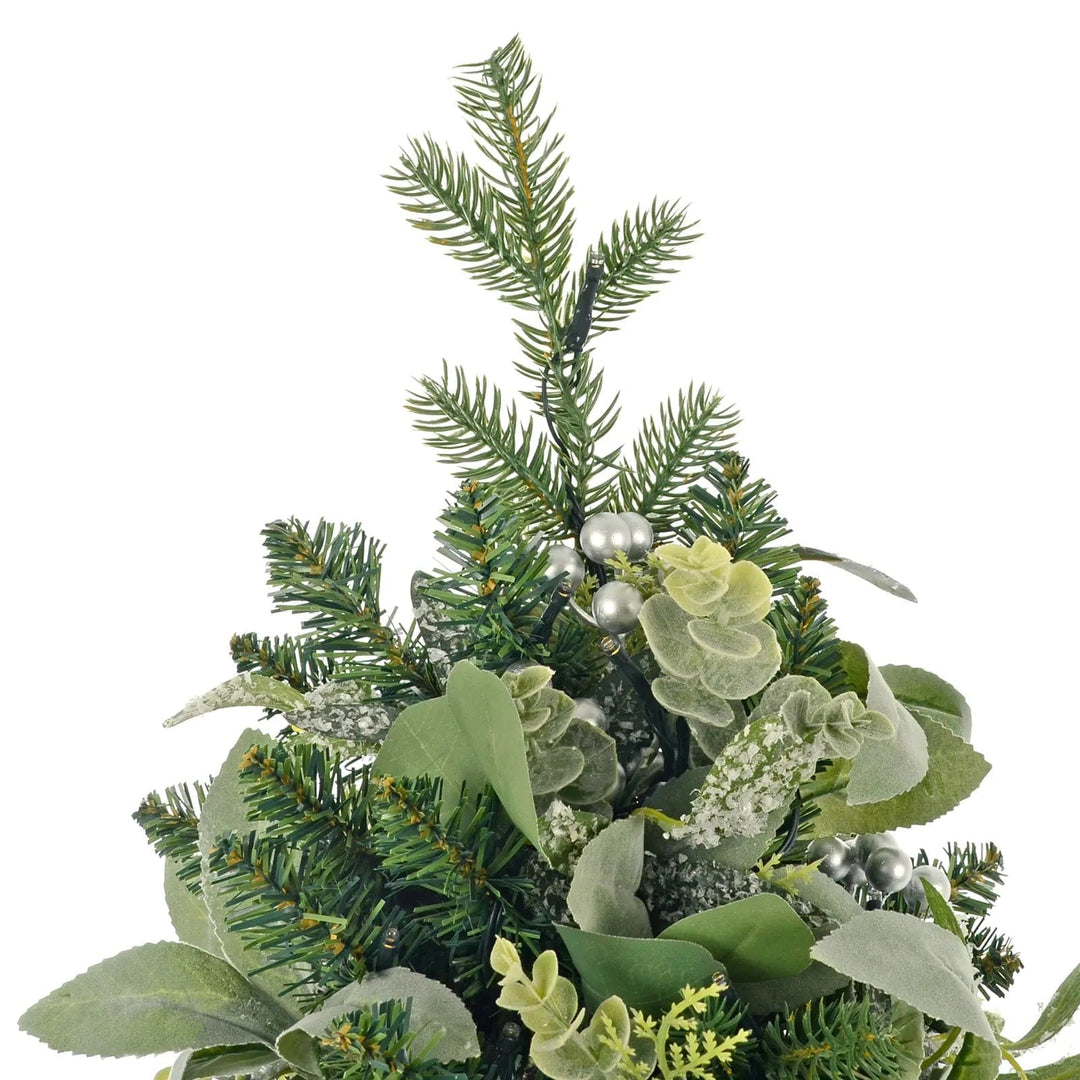 Close up of the top of a Christmas tree with lights, eucalyptus branches, frosted pine and silver berries