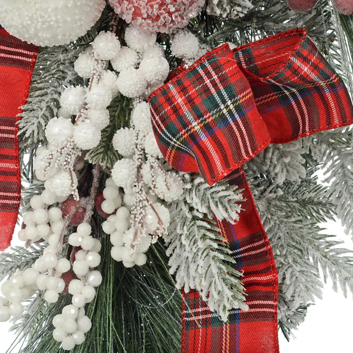 Close up detail of a red tartan ribbon, and white snowberries on a Christmas teardrop shape swag