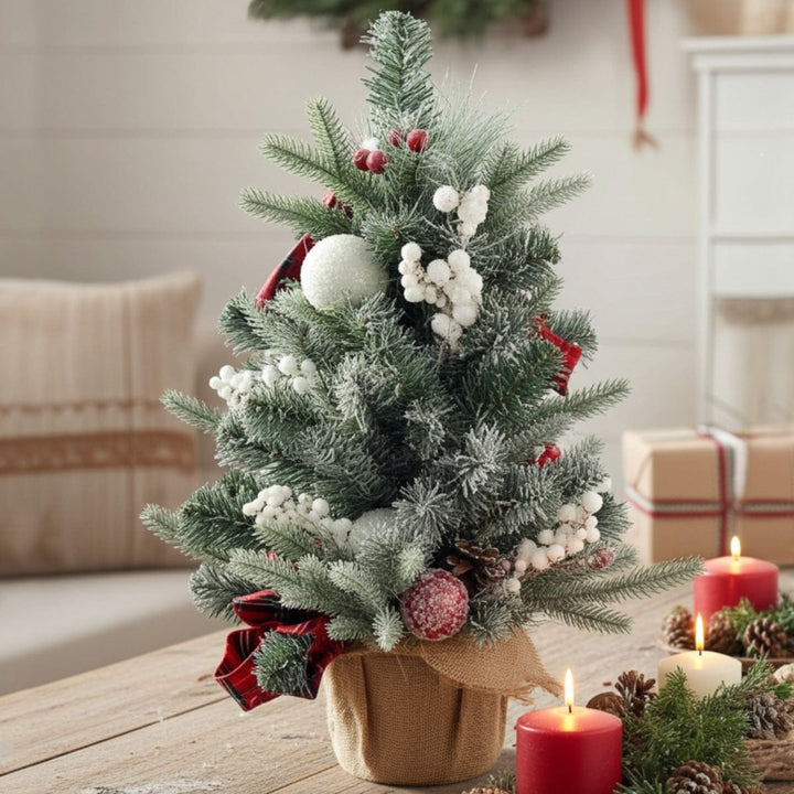 Decorated Christmas tree with red ribbons and white berries on a wooden table.