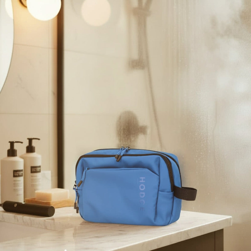 Blue toiletry bag on a bathroom counter with shower steam in the background