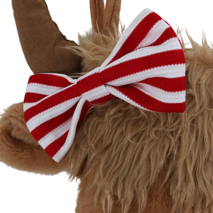 Close-up of a plush cow with a red and white striped bow tie on a white background