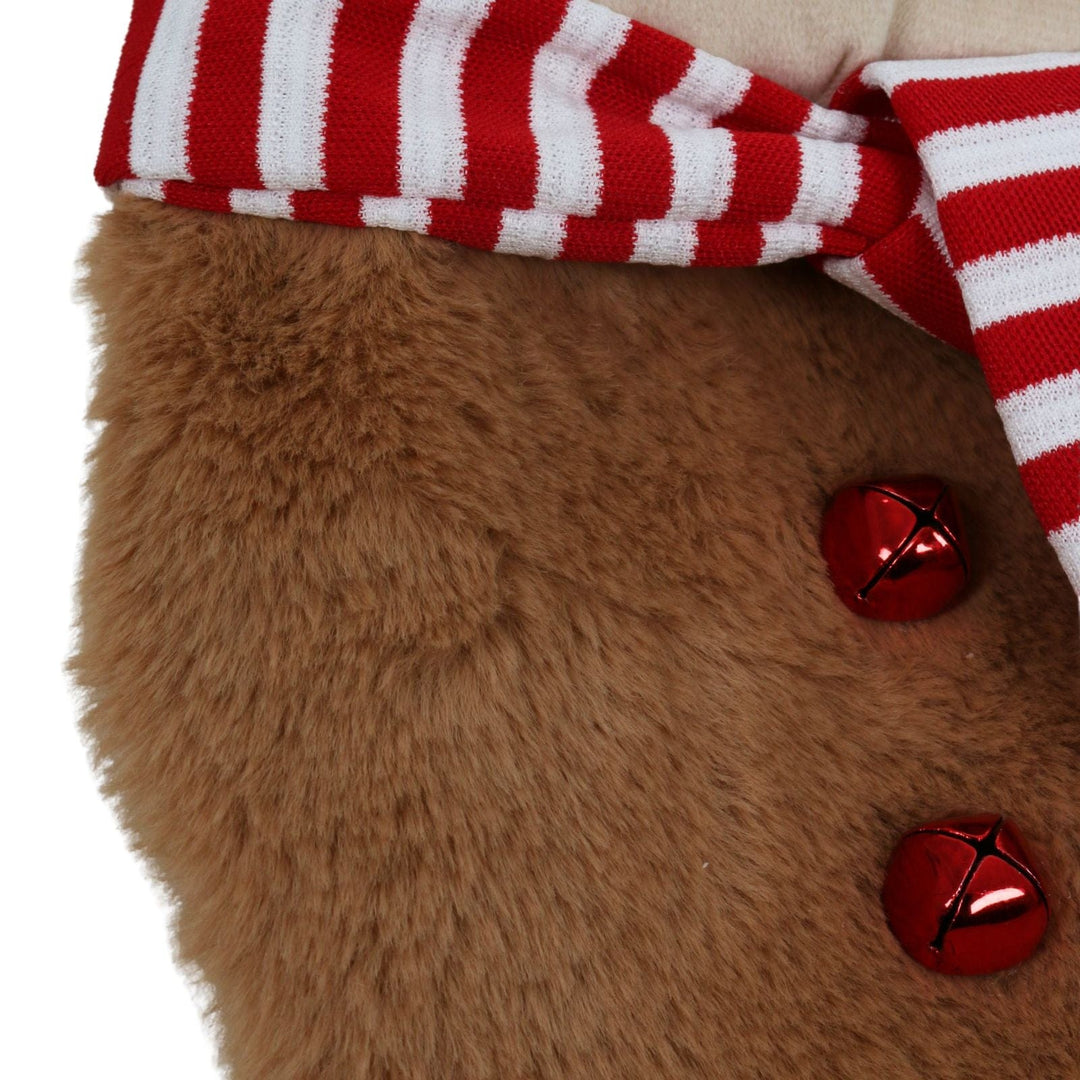 Close-up of a brown plush fabric with red and white striped fabric and red bells.