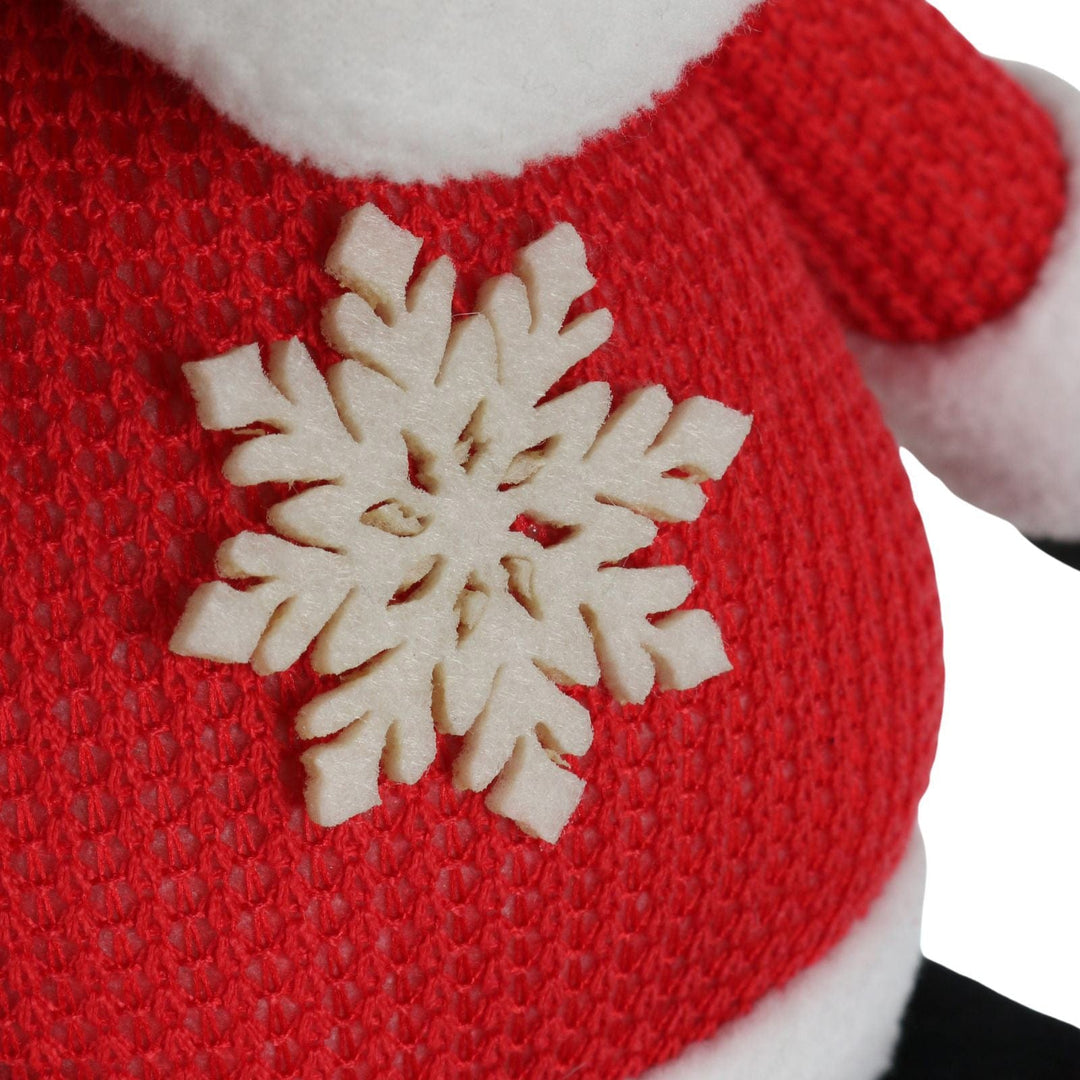 Close-up of a red jumper on figure with a beige snowflake design on a white background